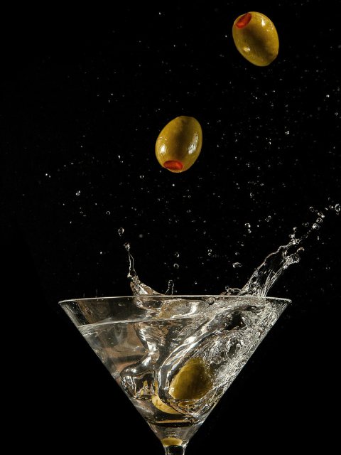 Olives splashing into a martini glass